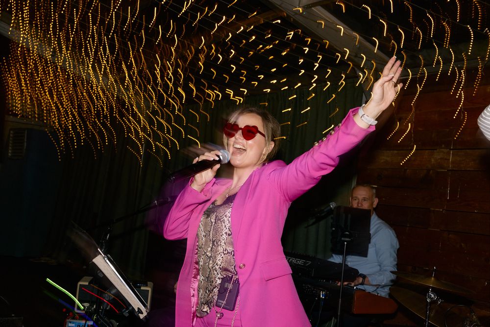 Party guests dancing and celebrating under colorful lights at a nighttime event.