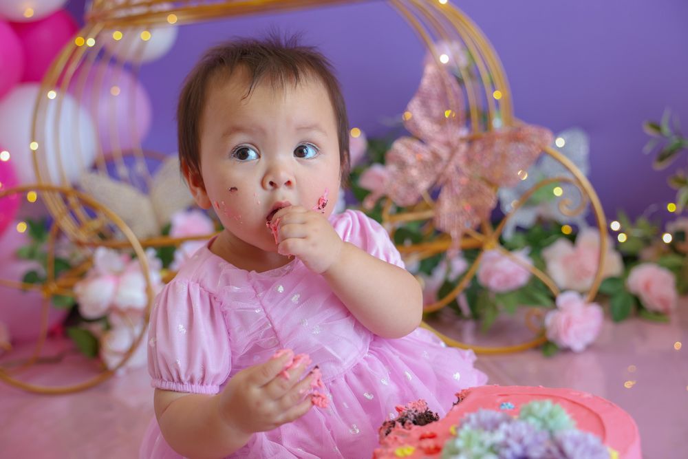 Baby girl enjoying eating cake on her first birthday during a cake smash session. Capturing the detail of the cake around her mouth.