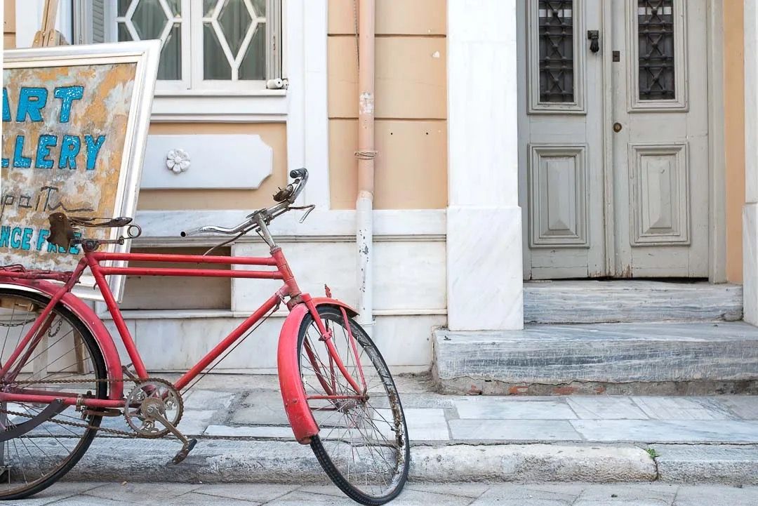 A bright red vintage bicycle parked against a beige building with classic architectural details.