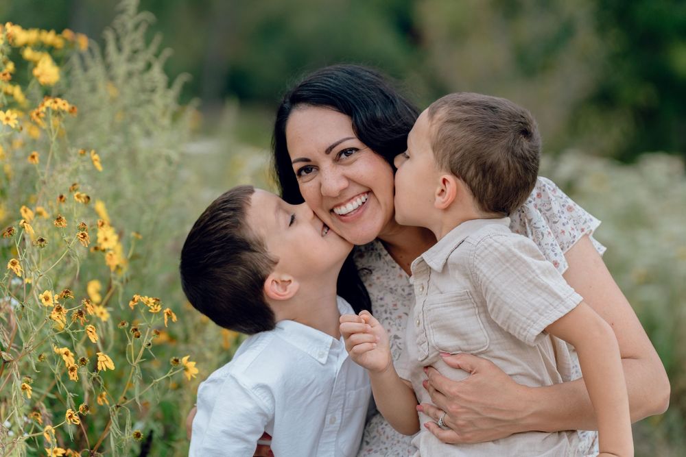 A family embraces lovingly in a field of yellow wildflowers during a sunny outdoor photo session in Akron, OH Cascade Valley Metro Park