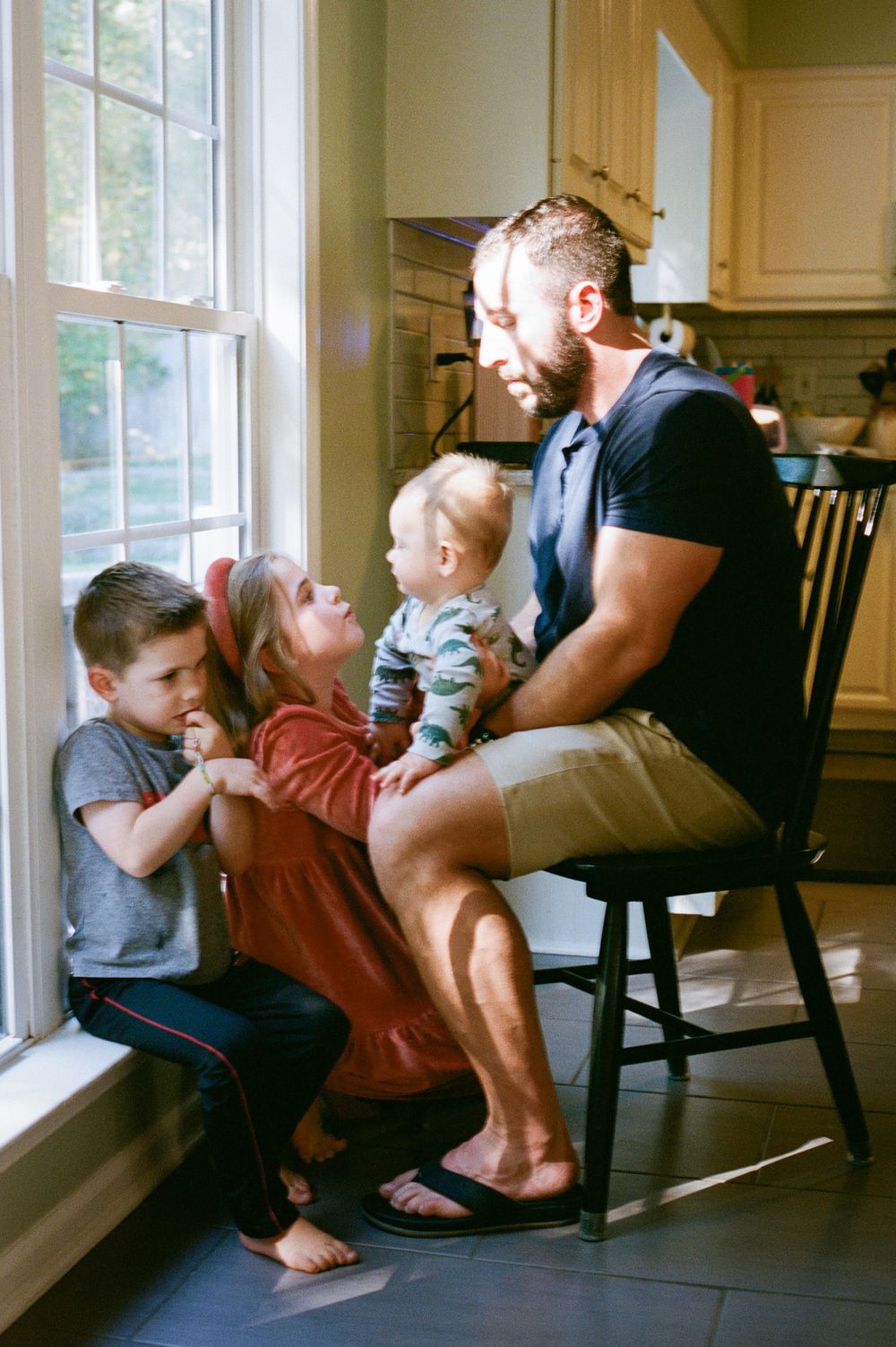 Family sharing a tender moment together by a bright window in their kitchen.