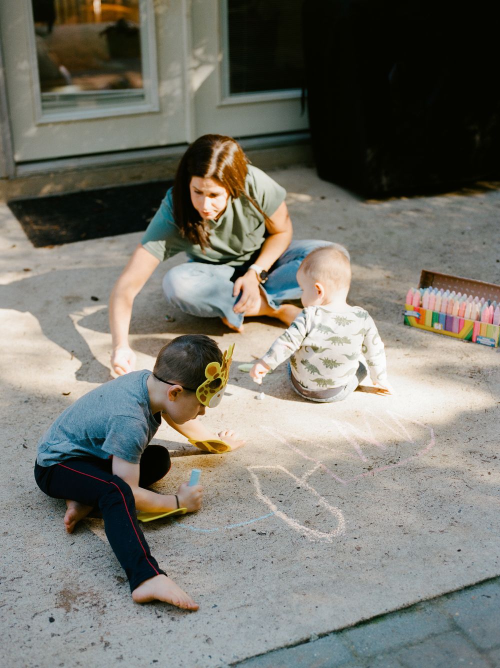Series of four photos showing someone drawing with chalk on a sidewalk in natural lighting.