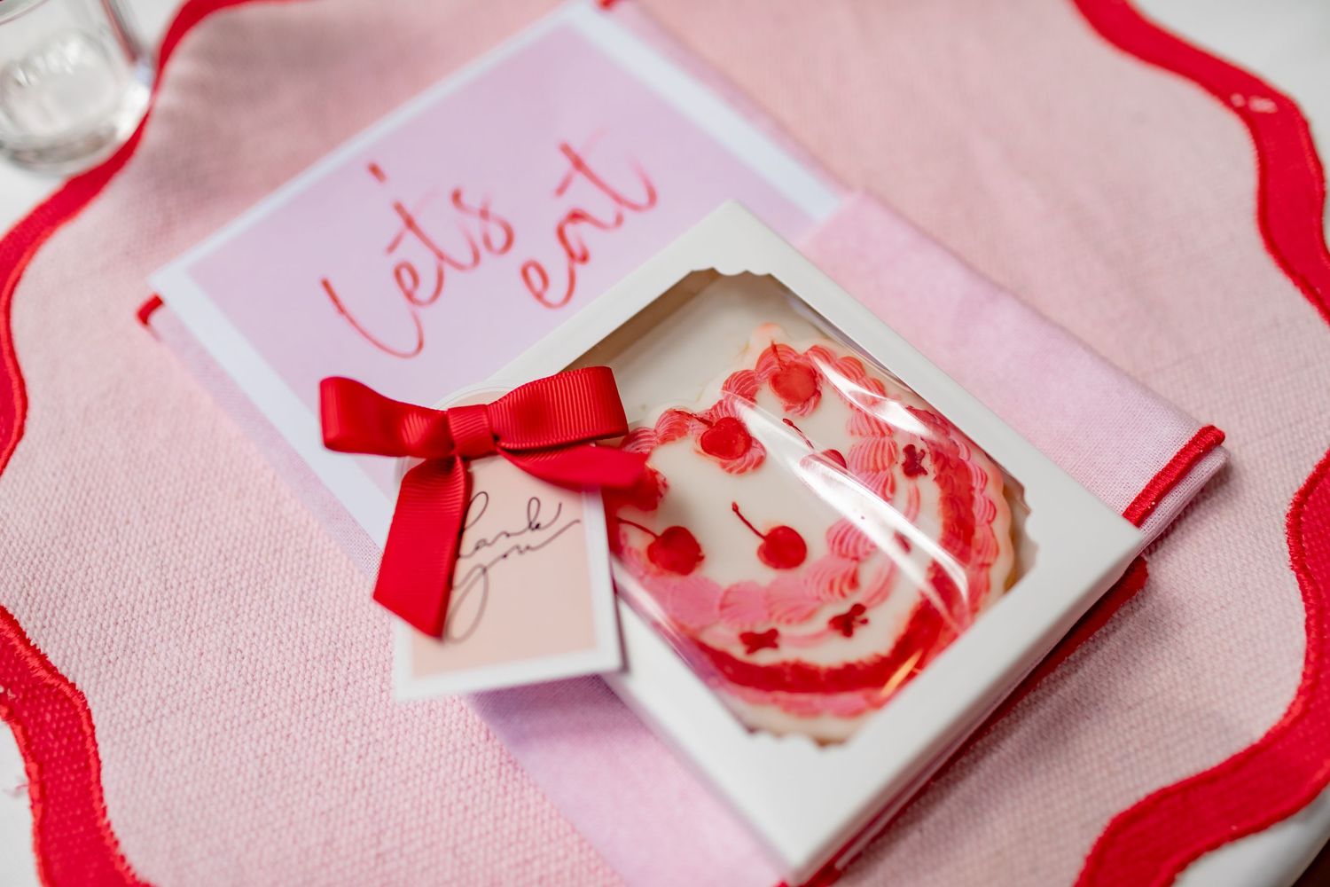 Decorative red ribbons and handmade Valentine's Day cards with hearts scattered on a pink background.