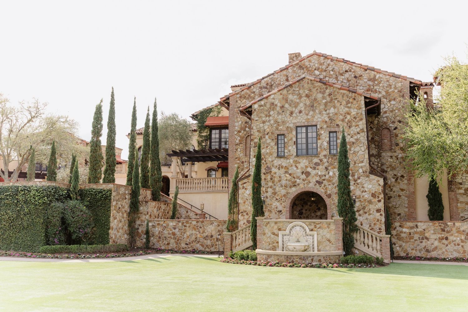 Rustic stone villa with Mediterranean architecture and cypress trees on manicured grounds.
