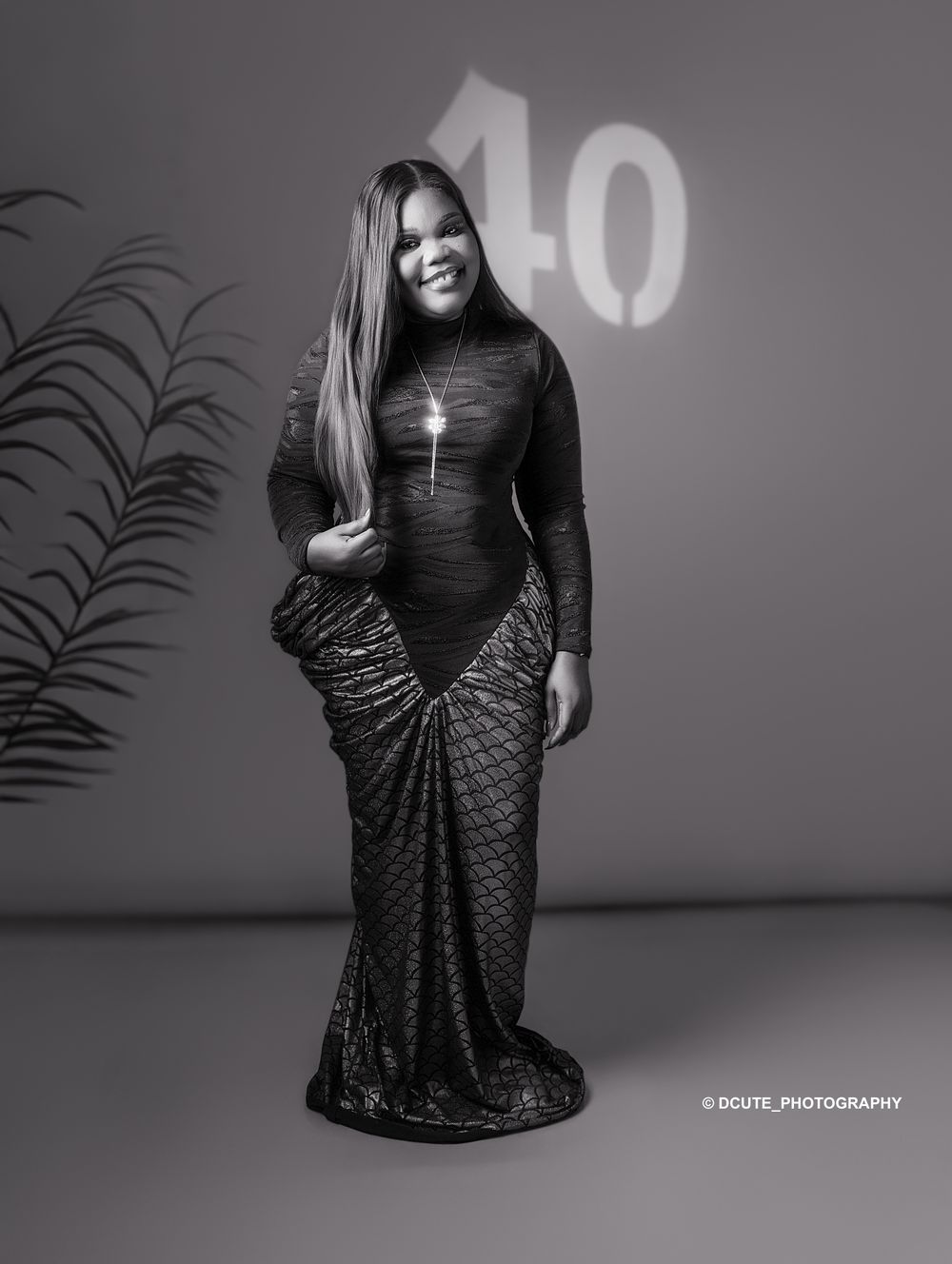 Black and white photo of a woman in an elegant mermaid gown posing at a 40th birthday celebration.