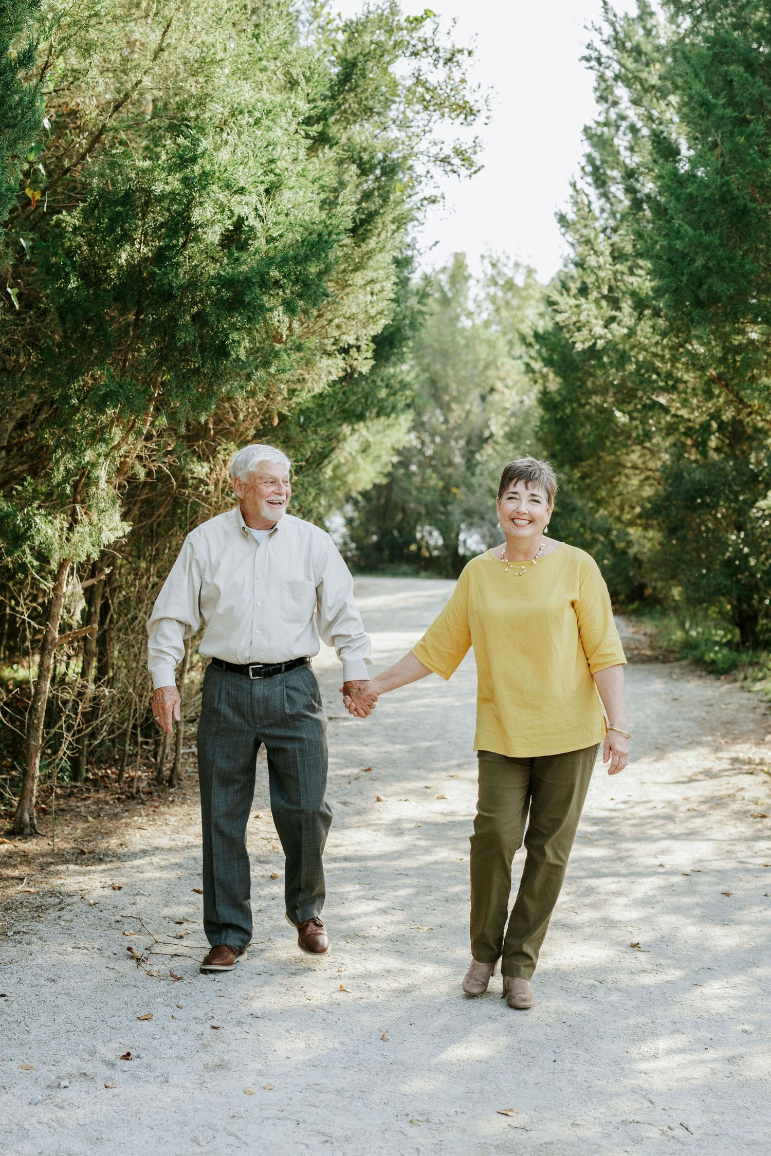 Five seniors walking together in a line on a dirt path with trees and greenery in the background.