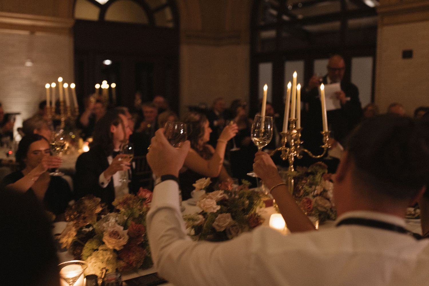 Elegant indoor wedding reception with candlelit tables and chandeliers creating a romantic atmosphere.