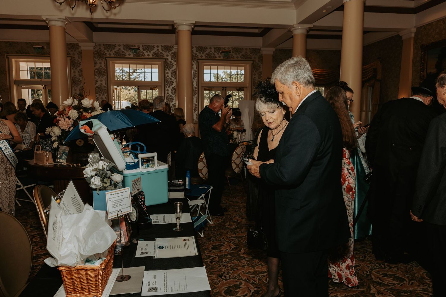 Professional networking event with attendees mingling and having discussions in an elegant hotel ballroom setting.
