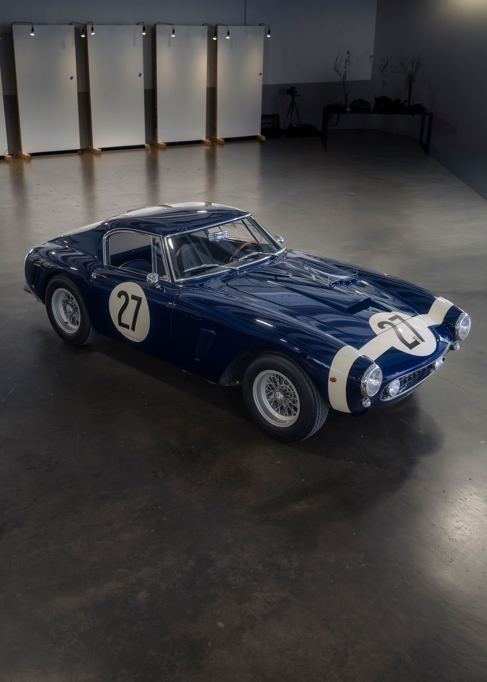 Classic blue Ferrari 250 GT racing car shown from multiple angles in a dimly lit studio space.