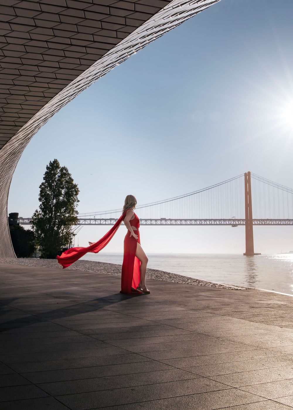 image of female in a red dress with bridge in background in Lisbon Portugal