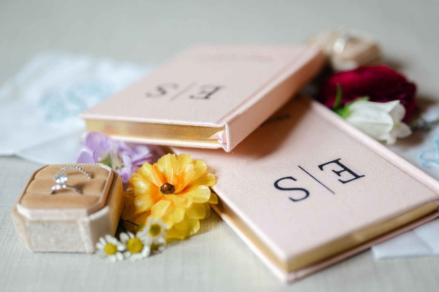 Scattered perfume bottles and cosmetic products arranged on a soft pink background with delicate floral accents.