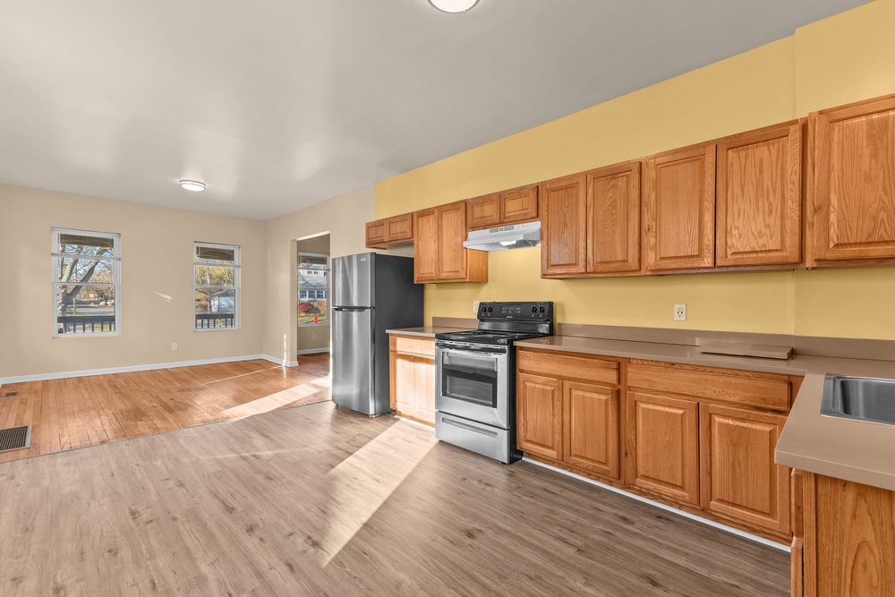 Kitchen featuring oak cabinetry, stainless steel appliances, hardwood floors, and open flow to living area.