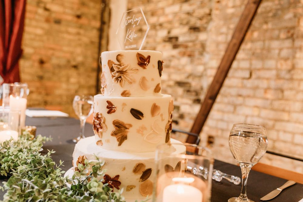 Elegant wedding reception setup with rustic brick walls, hanging lights, and floral arrangements on white-clothed tables.