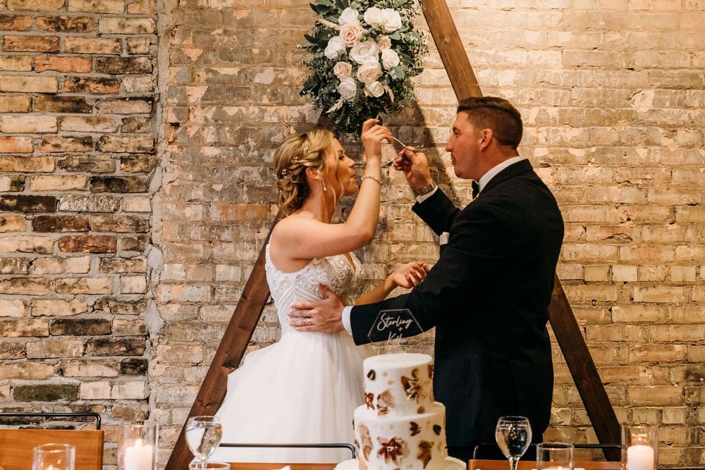 A couple shares romantic moments in front of an exposed brick wall during their wedding celebration.