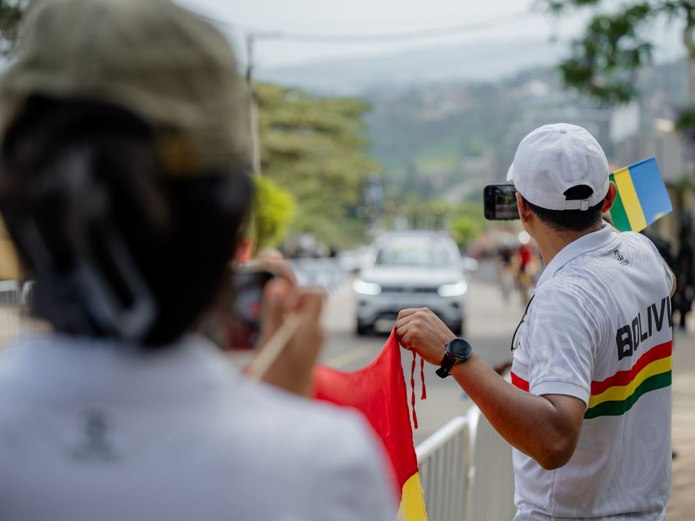 A group of photographers with cameras line up along a fence to capture photos at an outdoor event.