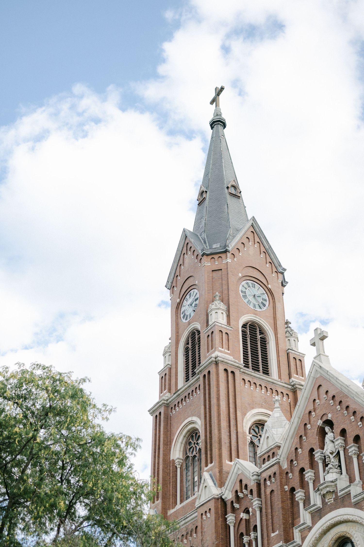 Gothic church spires with ornate architectural details rise against a cloudy blue sky in a striking architectural view.