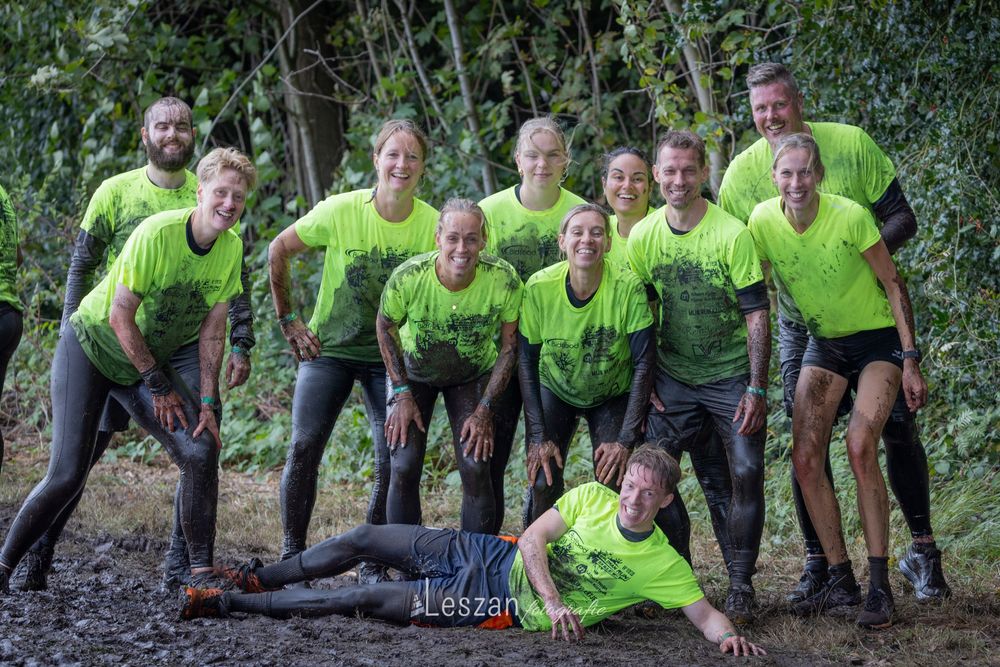 Group wearing neon yellow shirts performs pushups in sequence on outdoor trail during fitness activity.