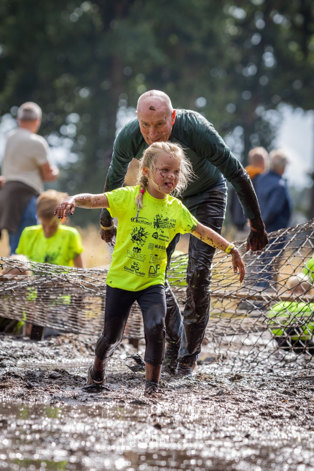 Athletes navigate challenging mud pit obstacles during outdoor adventure competition.