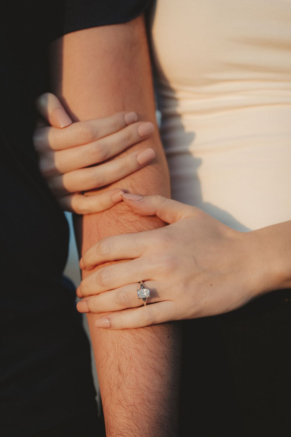 Close-up sequence of hands with an engagement ring casting dramatic shadows against a light background.
