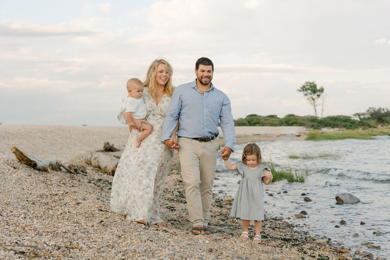 Family walking together on a rocky beach at sunset with ocean waves in background.