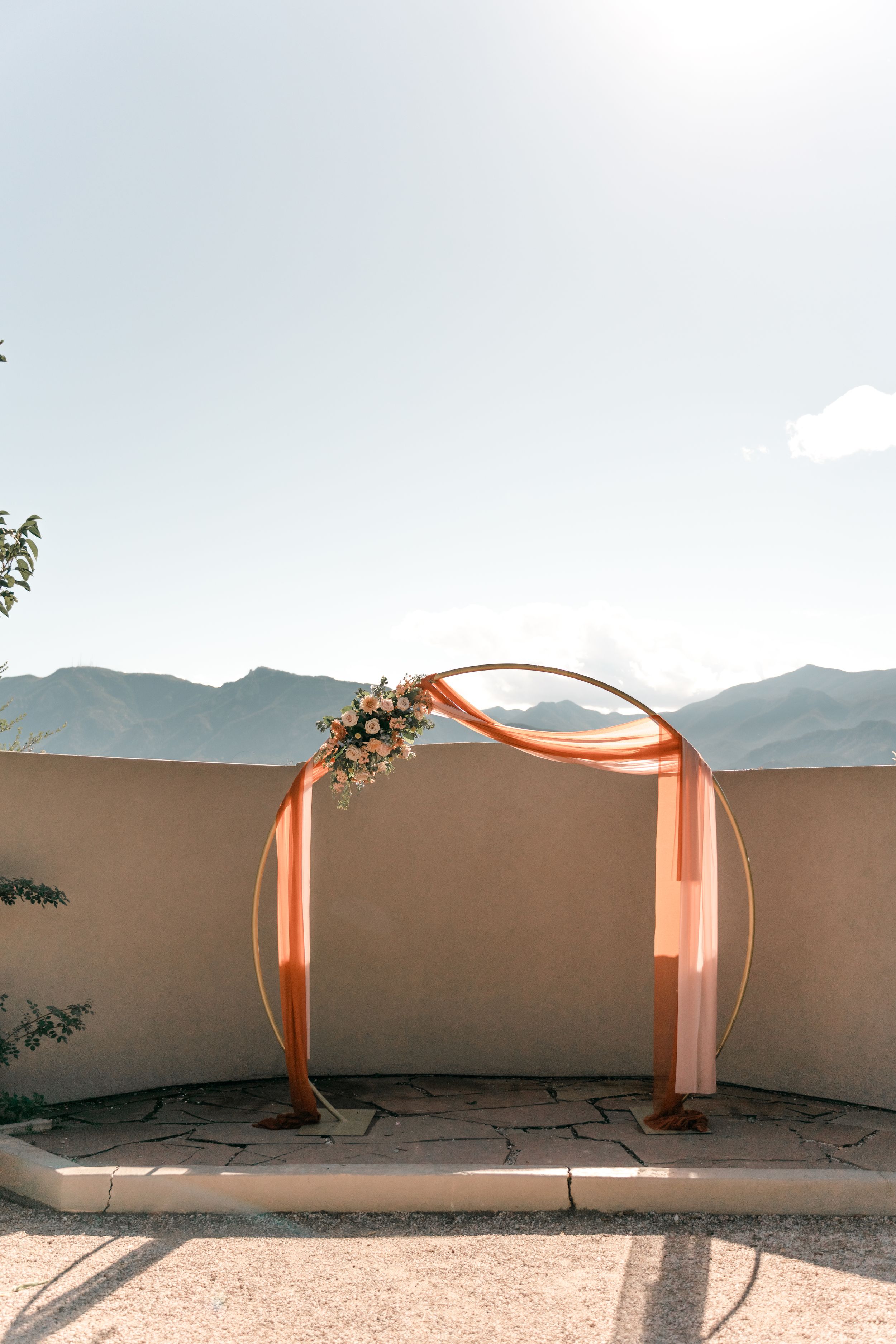 Peach-colored fabric draped across a curved wall installation creates an artistic architectural display against a cloudy sky.