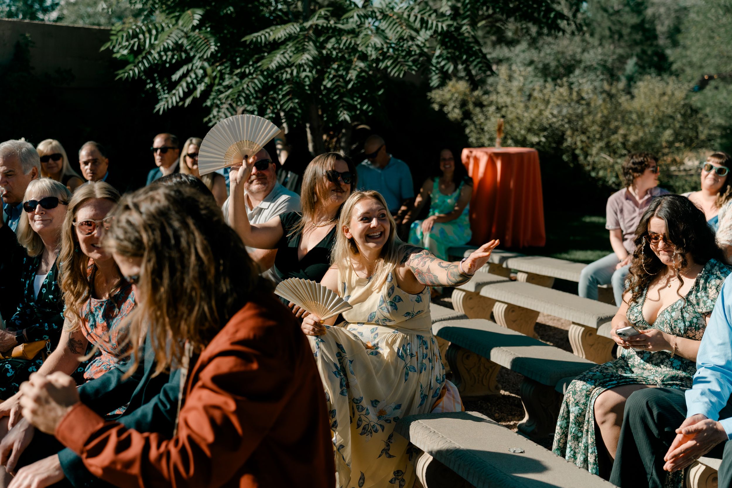 Guests mingle and socialize at an outdoor wedding reception with white tablecloths and natural decor.