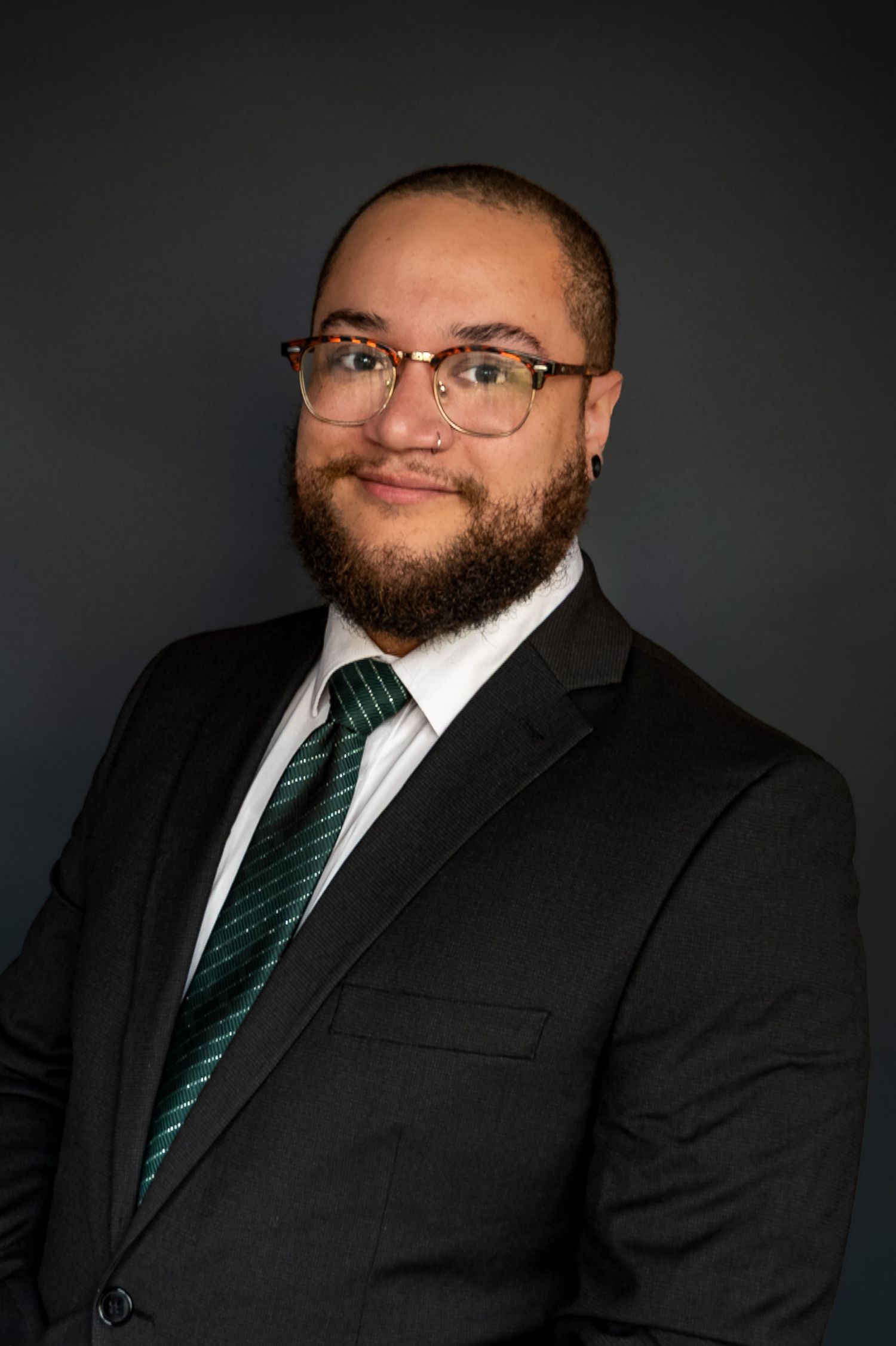 Professional headshot series showing a person in a black suit and striped tie against a dark background.
