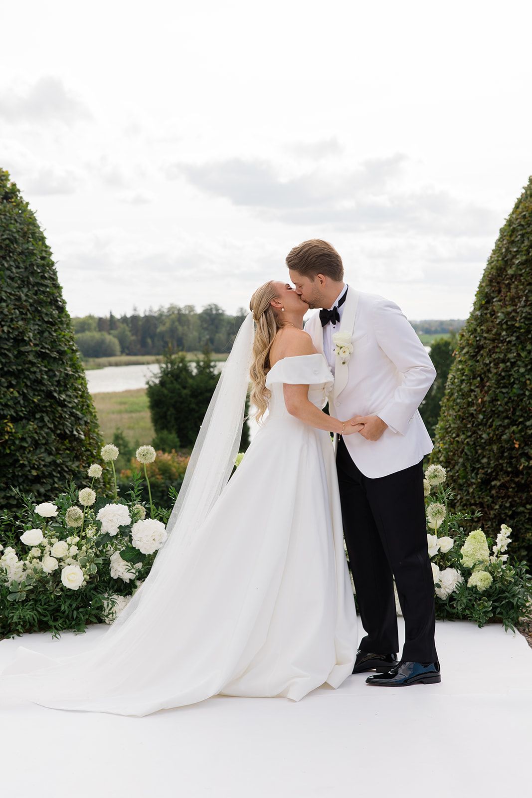 A romantic wedding moment captured in a series of photos showing a couple dipping and kissing in a garden with white roses.