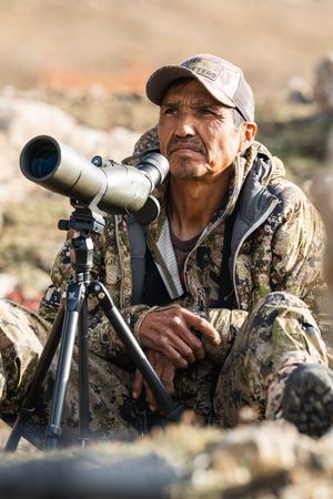 Person using spotting scope for wildlife observation in outdoor setting.