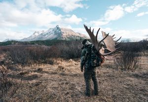 Group hiking through rugged mountain terrain with backpacks and outdoor gear in scenic wilderness landscape.