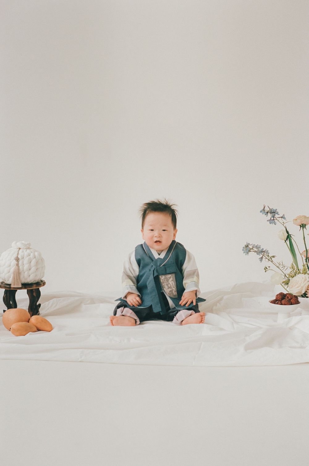 A series of minimalist photos showing a baby in different poses on white bedding wearing blue clothing.