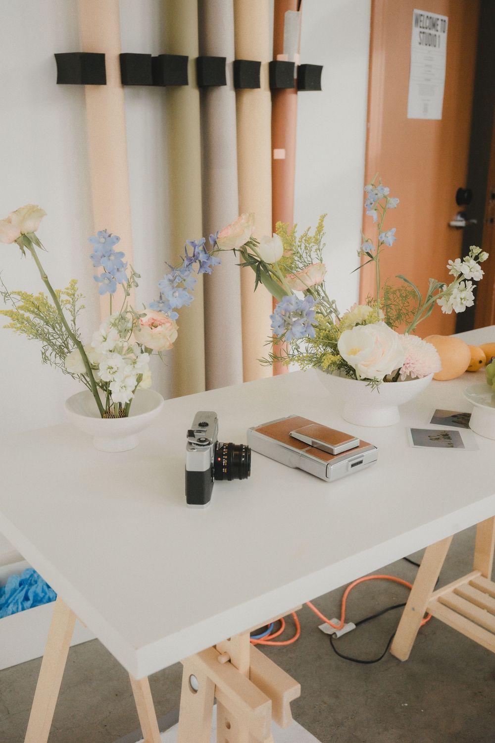 White table with wooden legs decorated with delicate floral arrangements and vases in a minimalist setting.