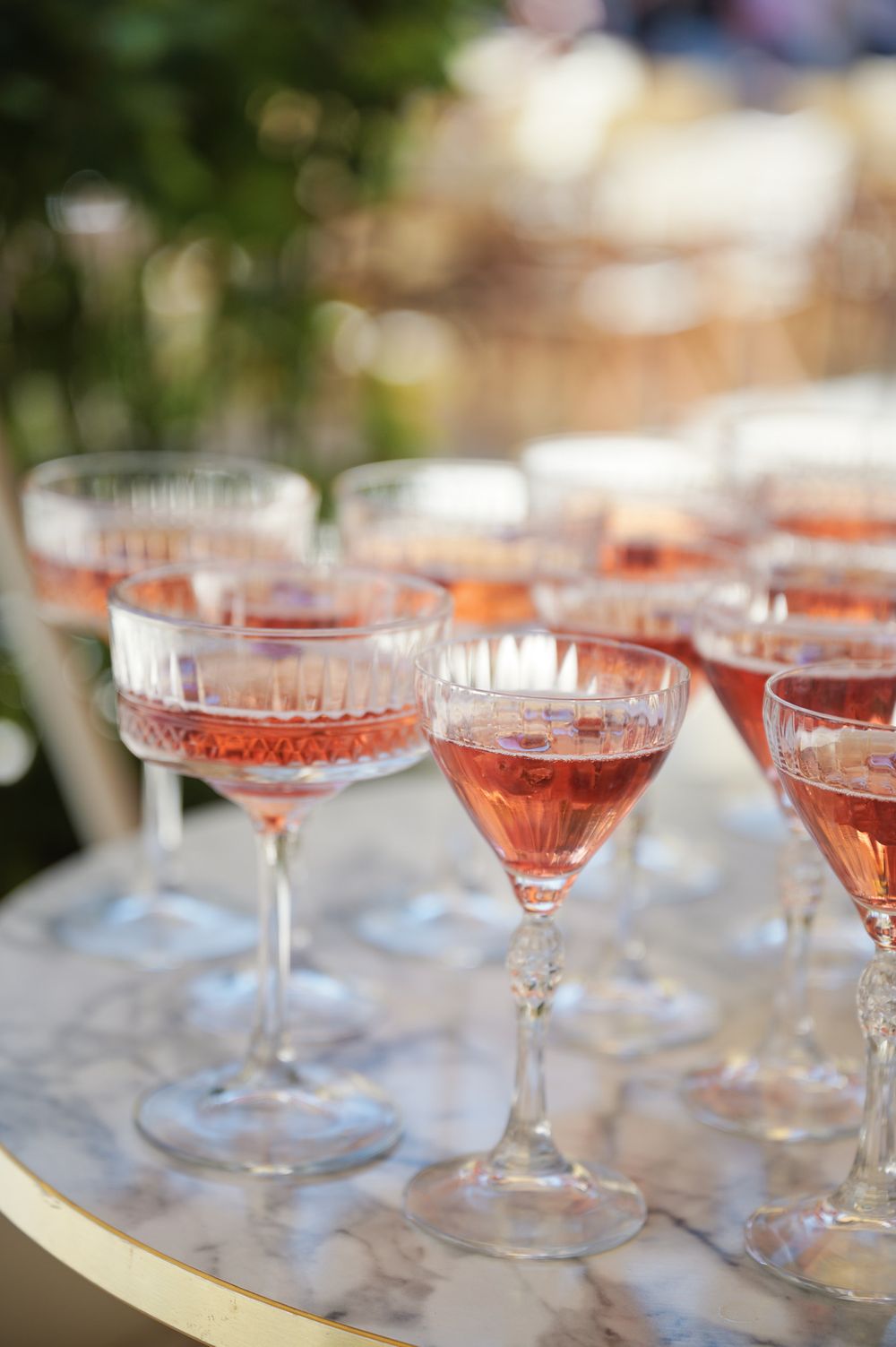 Elegant crystal champagne glasses filled with rose wine arranged on a marble surface.