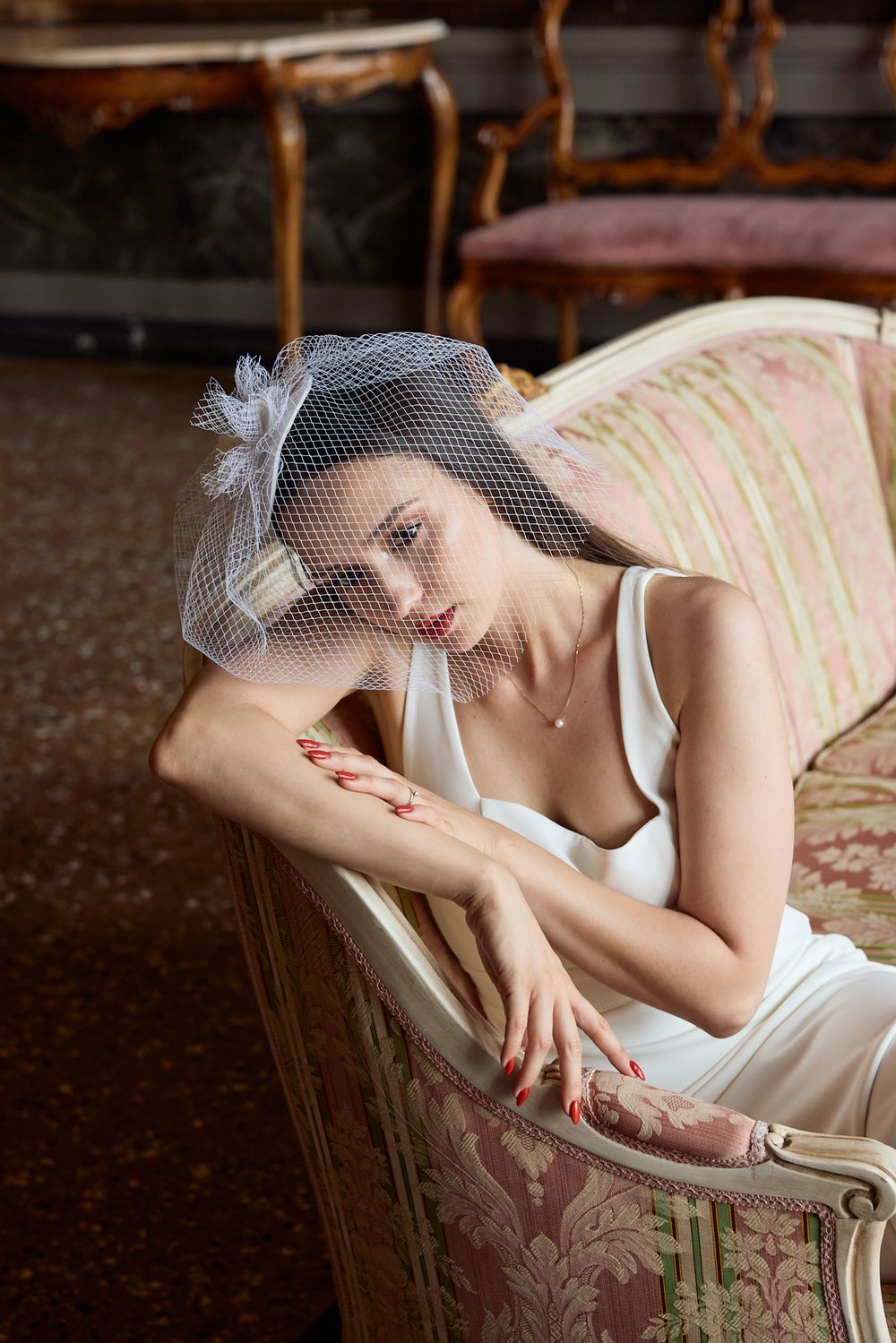 A bridal boudoir photo featuring delicate lace veil and vintage chaise lounge.