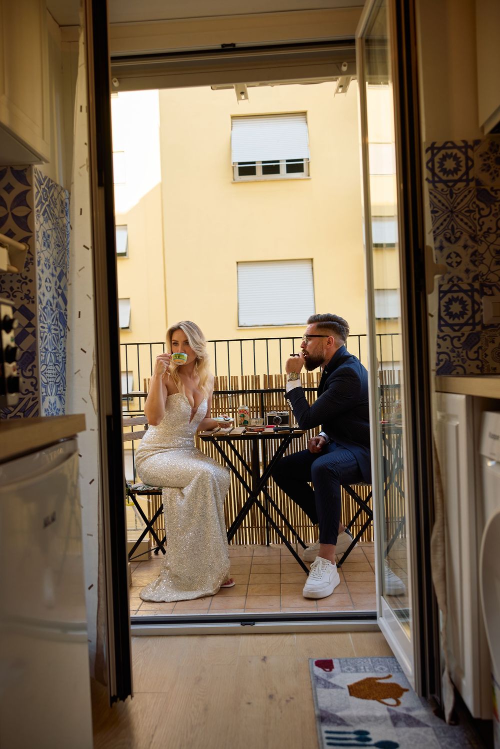 A couple shares an intimate moment on a balcony with decorative tile details and railings.