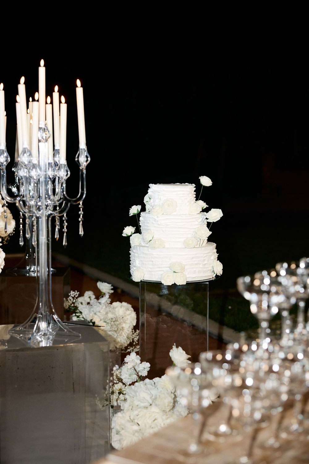 Crystal chandeliers and white wedding cakes create an elegant display at a luxury reception venue.