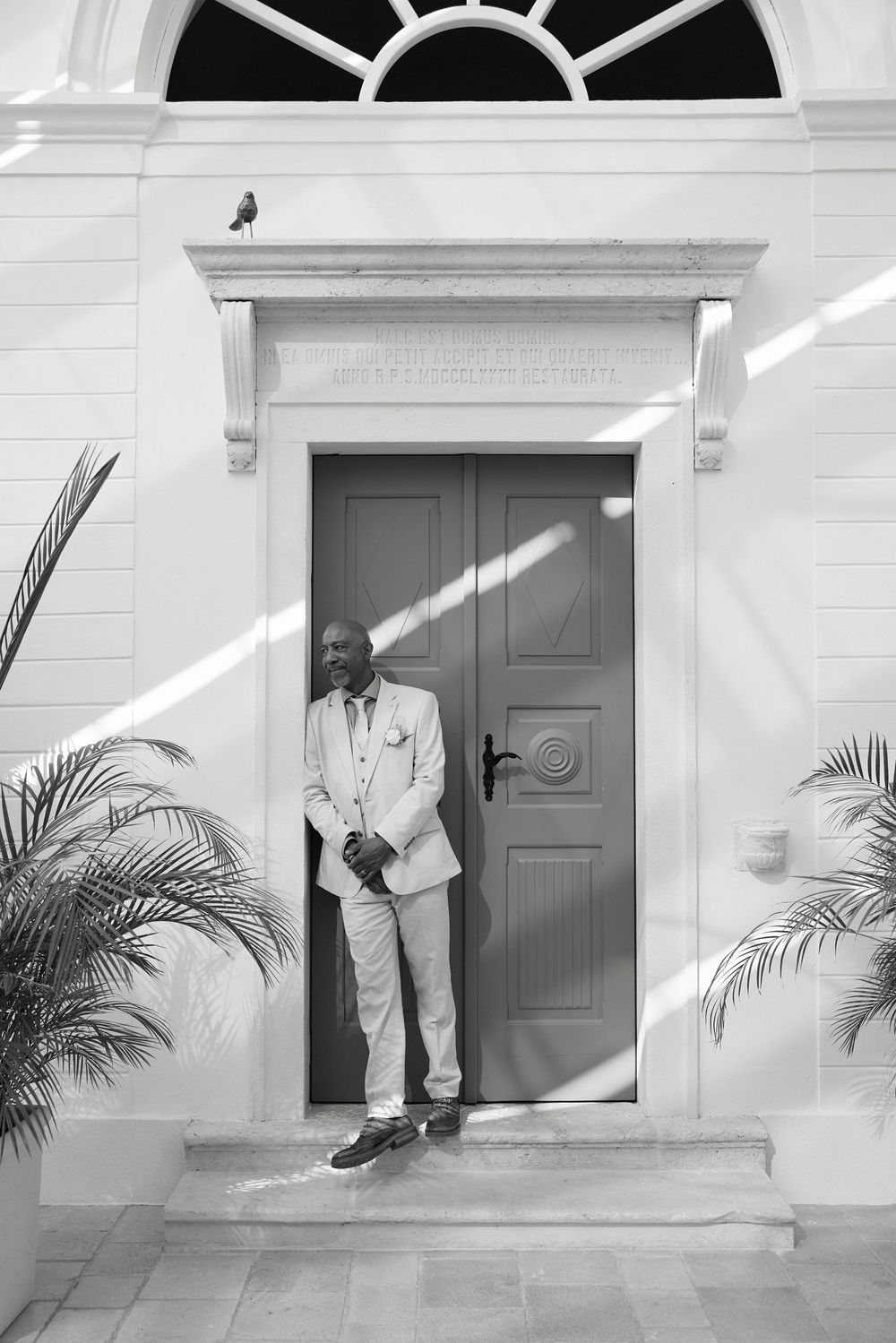 Black and white sequence showing doorway with palm plants and formal attire against white architecture.