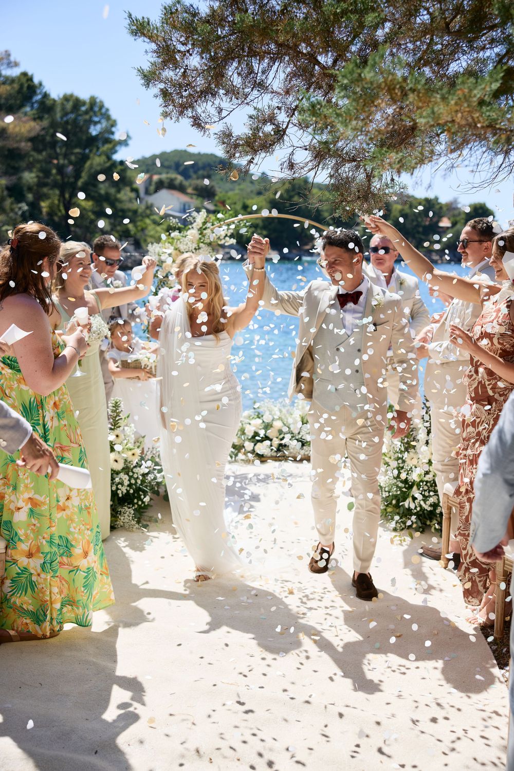 Wedding celebration with confetti being thrown during an outdoor ceremony by the sea.