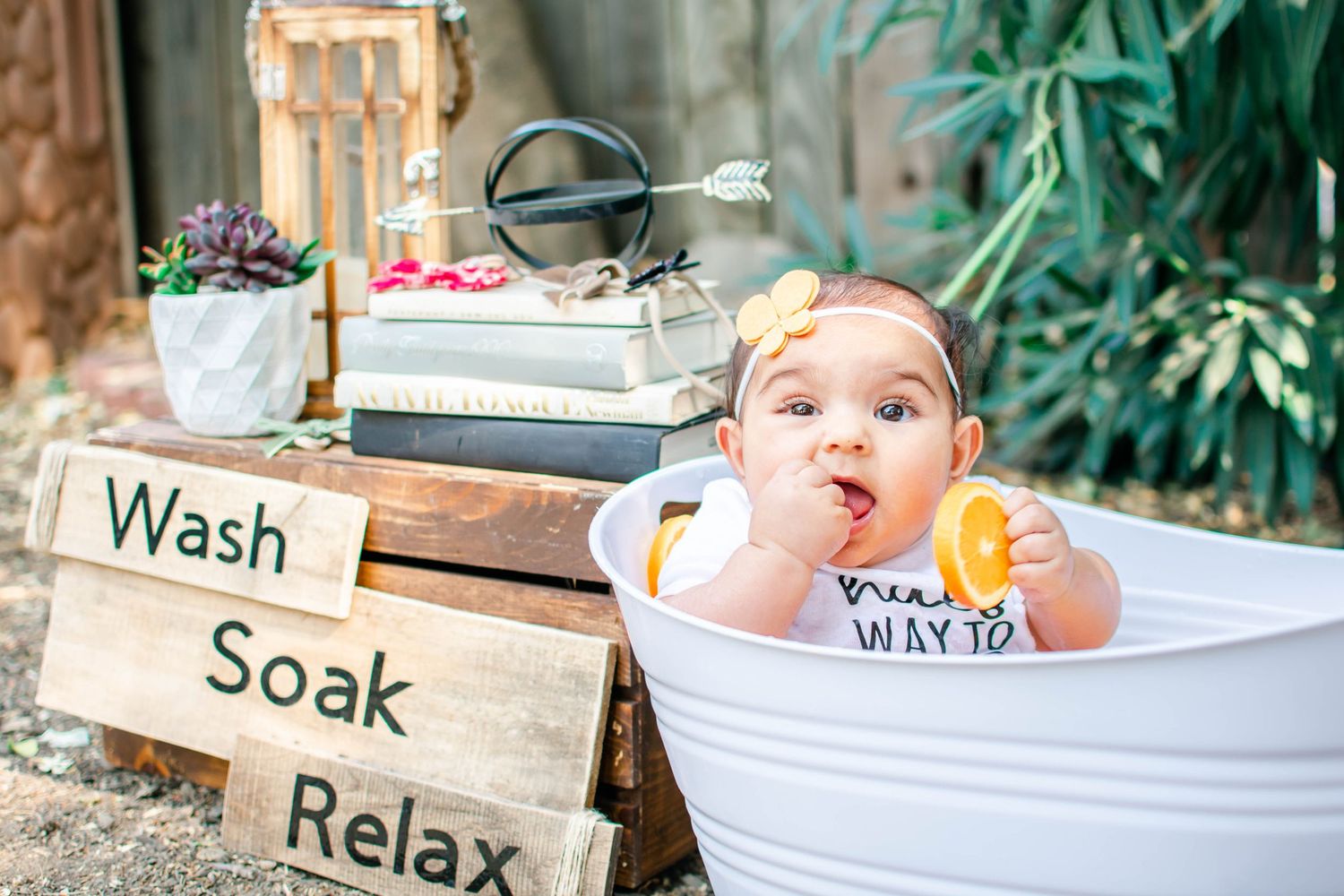 A creative photo series showing wooden signs with words 'wash', 'soak', and 'relax' next to white bathtubs in an outdoor setting.