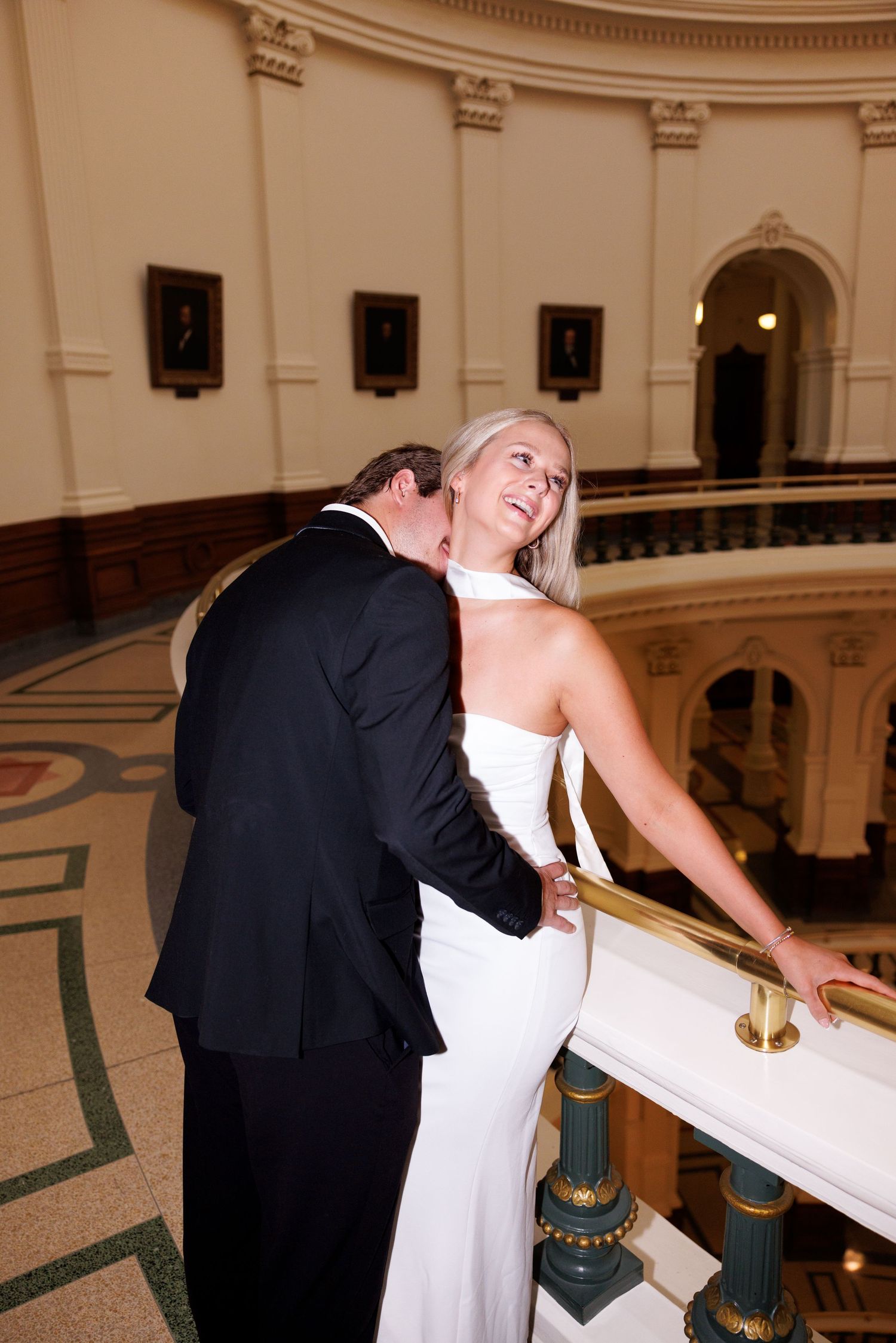 Couple sharing romantic moment on ornate marble staircase in formal attire.