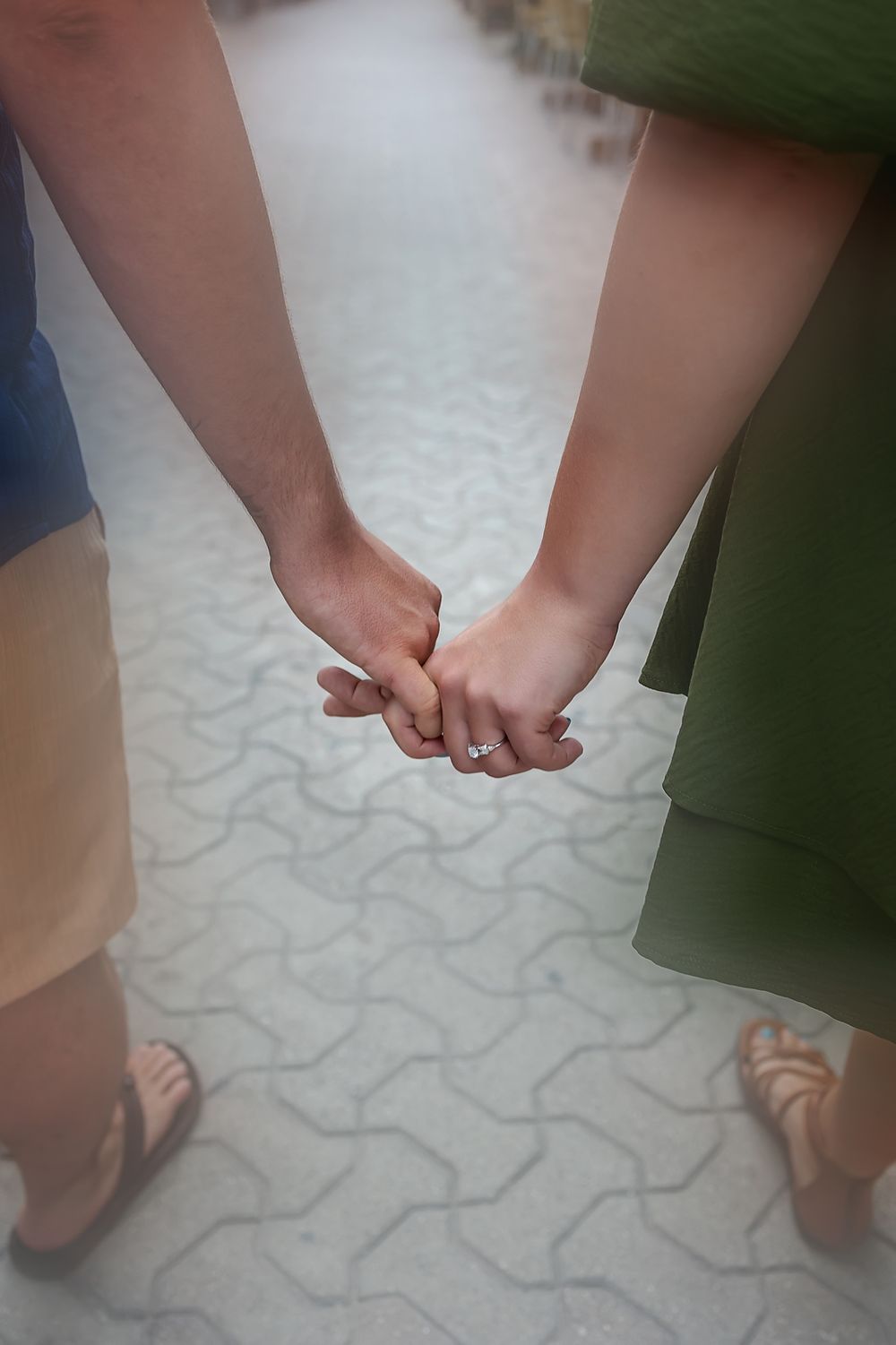 Close up of hands held together while walking on a textured stone path.