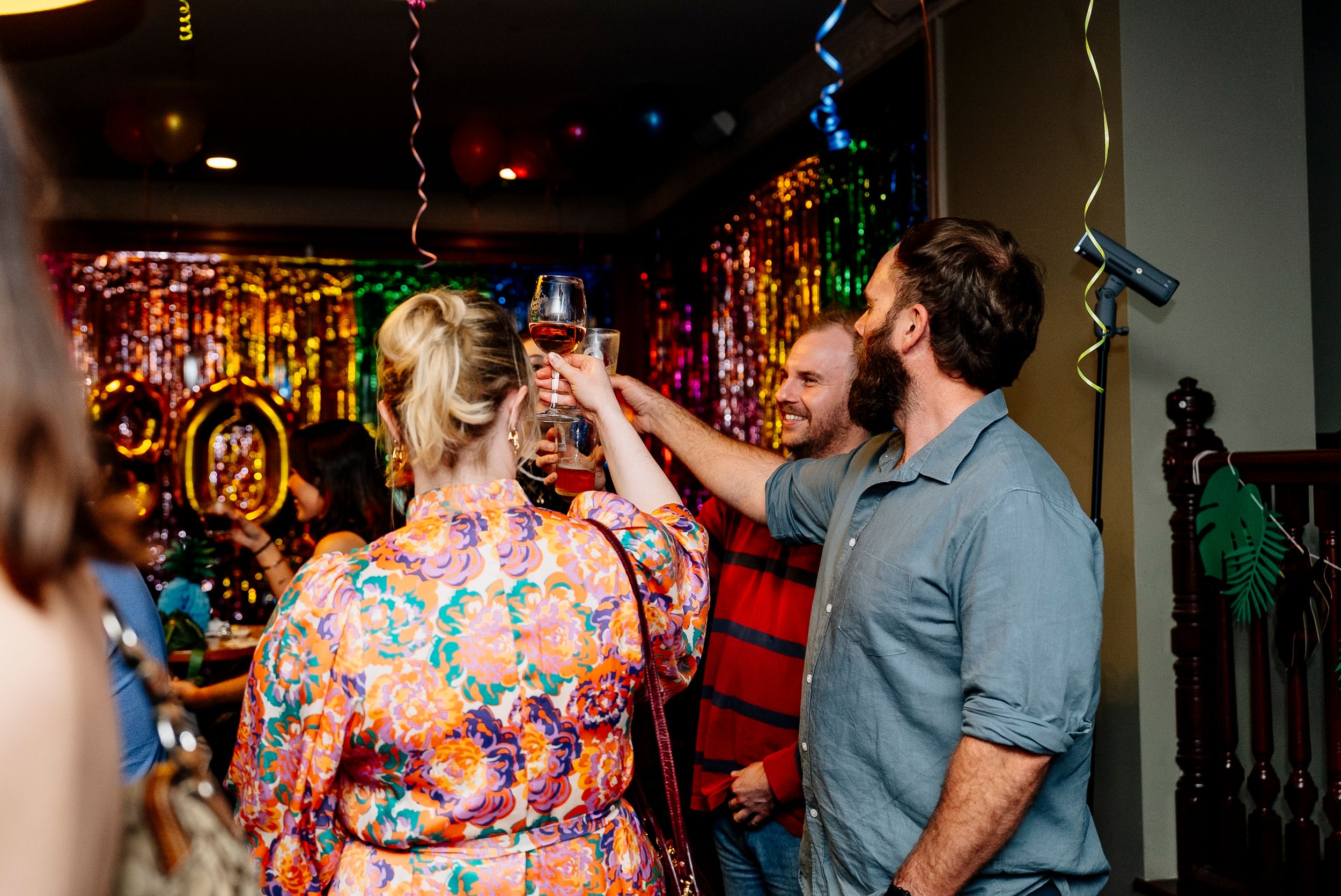 People dancing and celebrating at a lively bar or nightclub with colorful lighting and festive atmosphere.