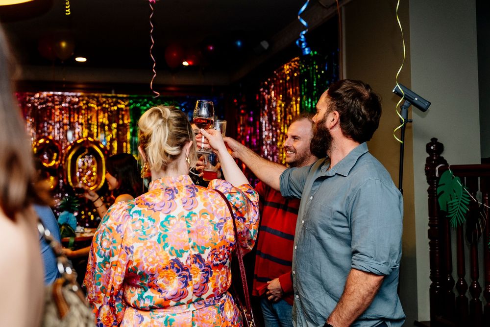 People dancing and celebrating at a lively bar or nightclub with colorful lighting and festive atmosphere.