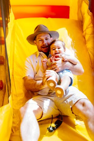 A sequence of four yellow-tinted photos showing a parent and baby playing together on a bright surface.