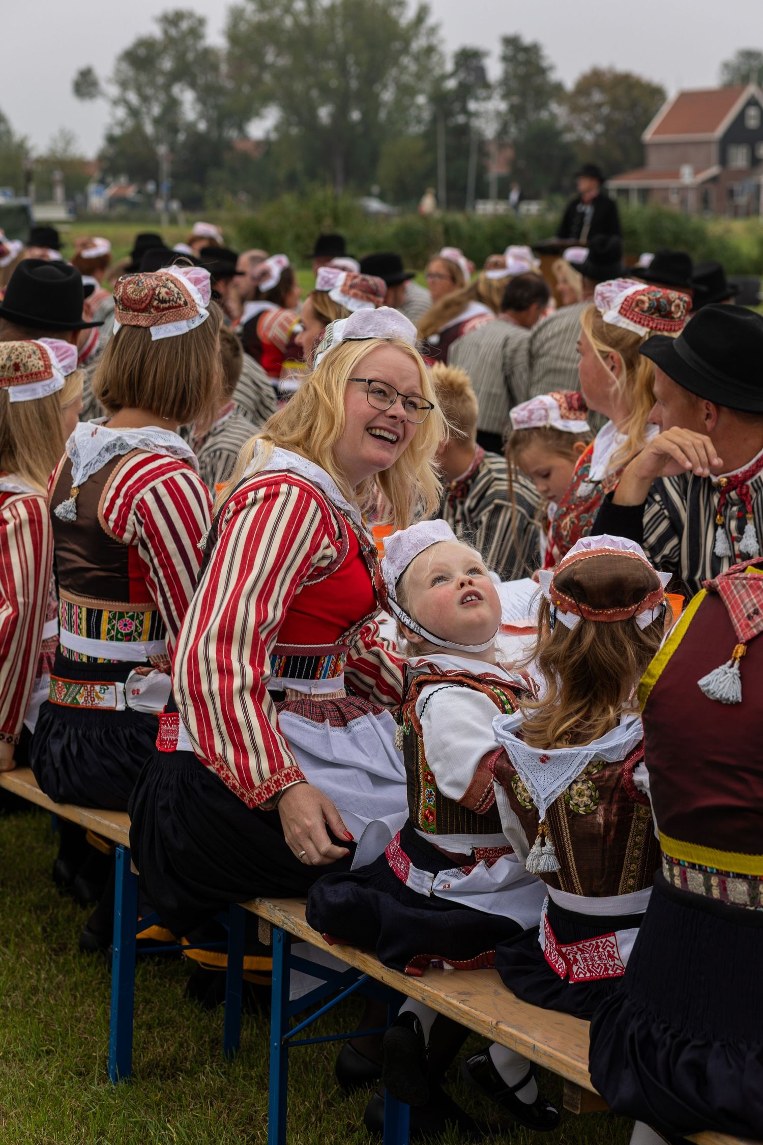 Festival attendees wearing traditional red and white striped folk costumes enjoy a cultural celebration outdoors.