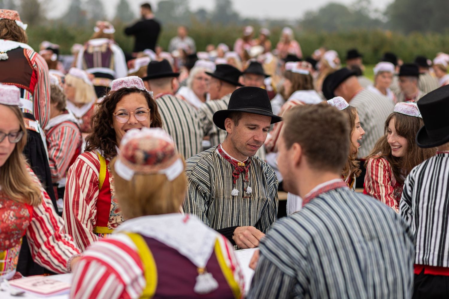 Crowd wearing traditional striped and red costumes celebrates at a cultural festival outdoors.