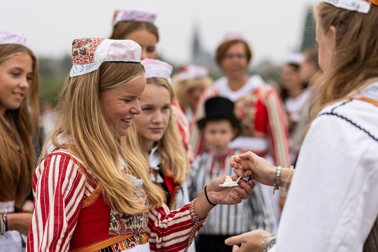 A crowd of people wearing red and white traditional clothing celebrate at a festive outdoor gathering.