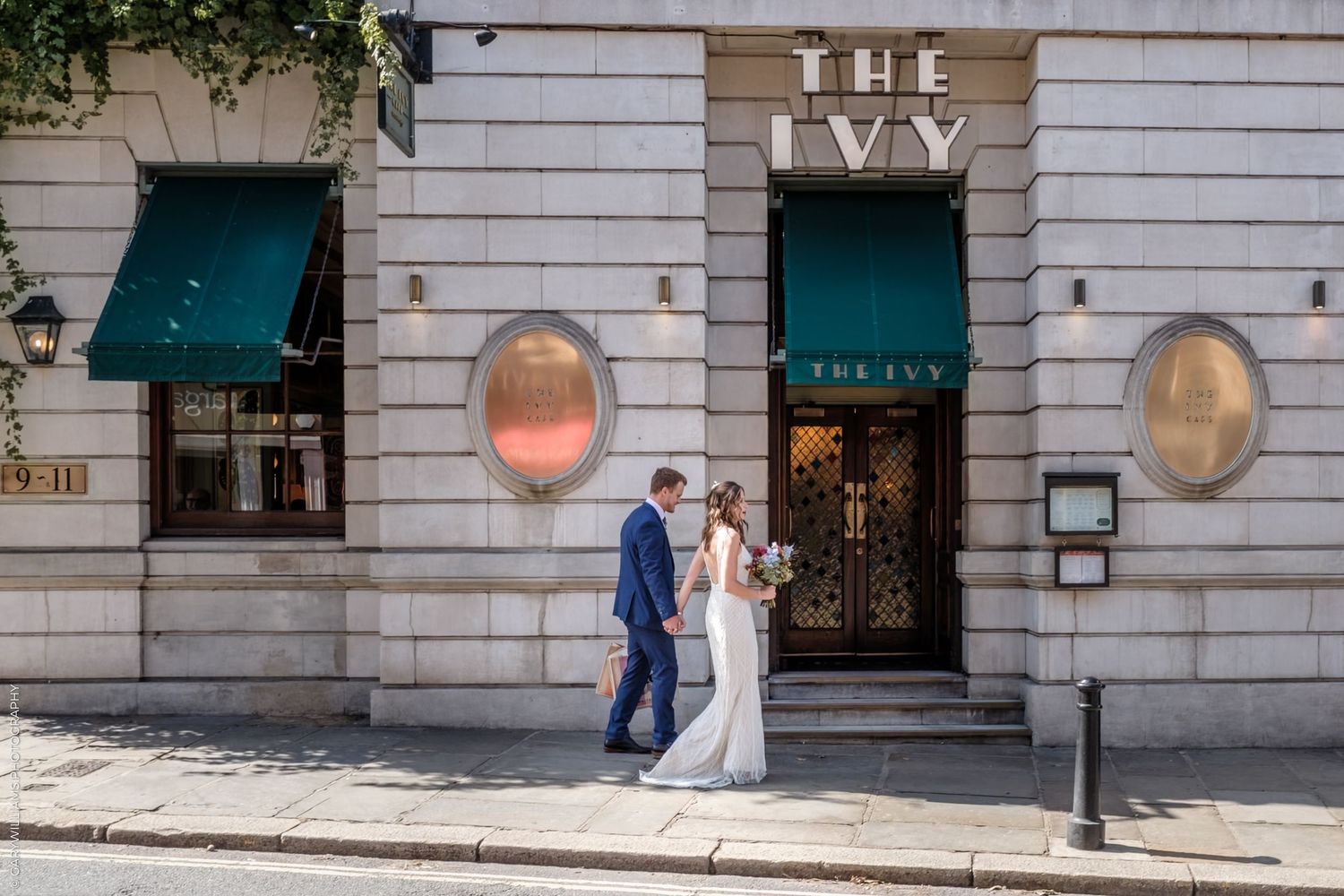 A row of storefronts along a city sidewalk with teal awnings and stone facades.