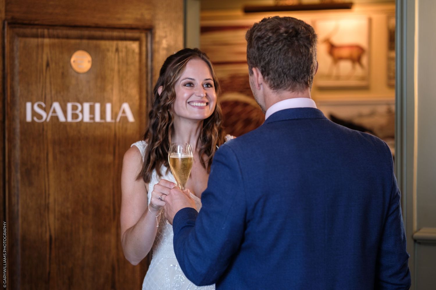 A person wearing a white dress walks through an elegant venue entrance marked by Isabella signage.