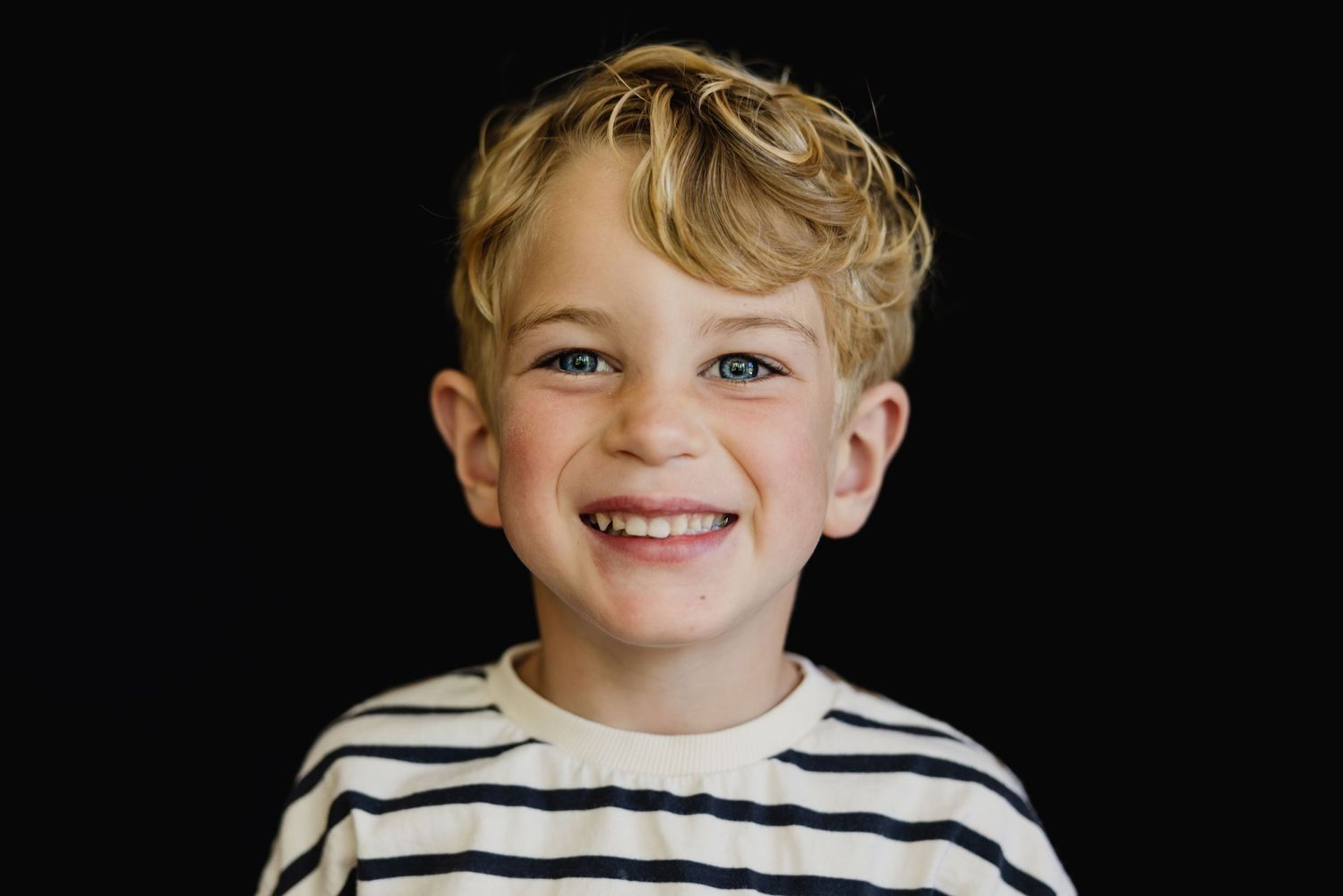 Seven close-up photos of a youth wearing a striped shirt against a dark background.